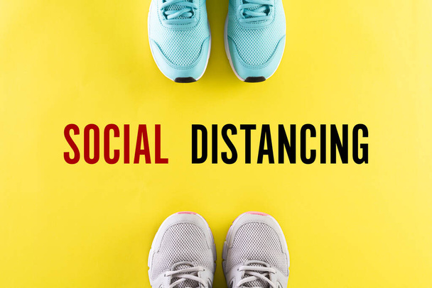 社会的距離概念。緑のピンクのパステルを背景に支配者のいる靴は、社会的距離概念を使用してコロナウイルスが拡散するのを止めることで. - 写真・画像