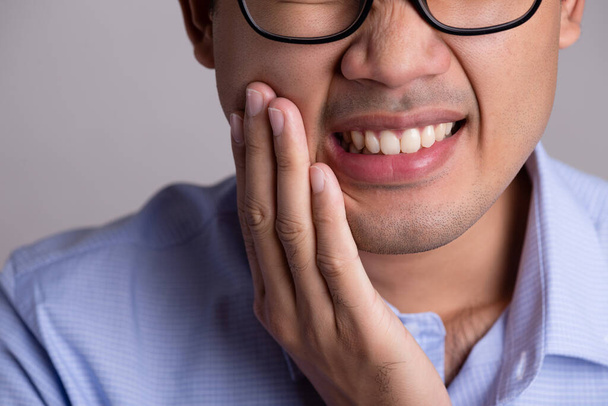 Jovem asiático homem com dentes sensíveis ou dor de dente. Conceito de saúde
. - Foto, Imagem