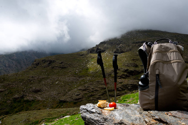 hiking sticks with lunch and backpack at mountain range in sierra nevada, spain - Photo, Image