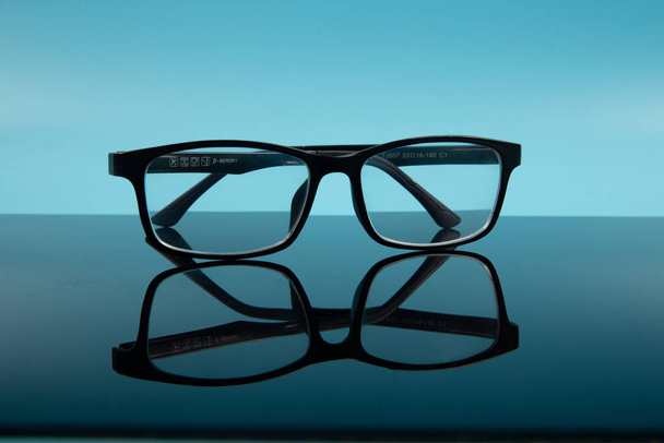 černý rám brýle brýle s odrazem na modrém pozadí. - Fotografie, Obrázek