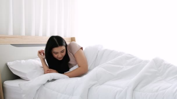 Schattige aziatische vrouw wakker in de ochtend, oefenen op het bed met armen strekken en draaien. - Video