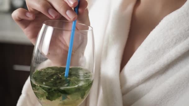 Girl is drinking mojito. Female hands bring mojito glass to their faces and drink through straw. Close-up - Footage, Video