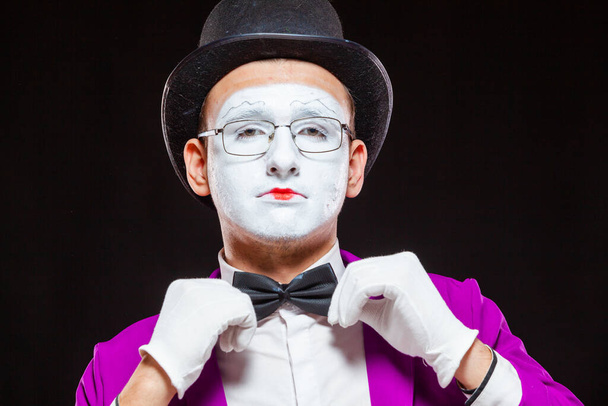 Portrait of male mime artist, isolated on black background. Close up of man face. Man adjusts his bow tie - Fotografie, Obrázek