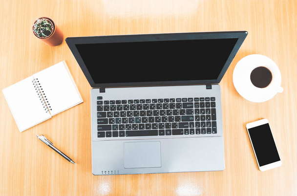Foco seletivo, vista superior do desktop de madeira com laptop, telefone celular em branco, caneta, xícara de café, cacto e notebook
 - Foto, Imagem
