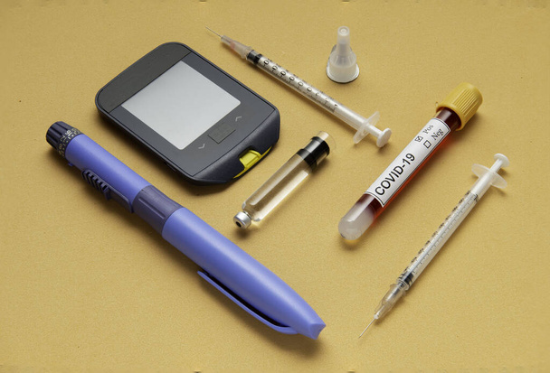 Koronavirus představuje největší riziko pro diabetes. Inzulínové pero, diabetická injekční stříkačka, test cukru v krvi na oranžovém pozadí - Fotografie, Obrázek