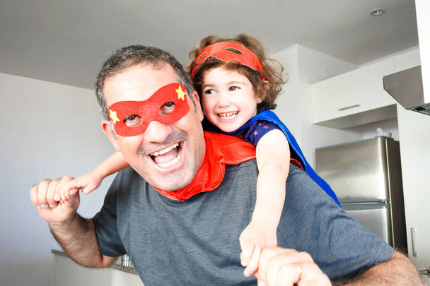 Ojciec superbohatera (40 lat) i córka superbohatera (03 lata) udają, że bawią się razem w domu. Wspierająca koncepcja męskiego rodzicielstwa. Prawdziwi ludzie. Przestrzeń kopiowania - Zdjęcie, obraz