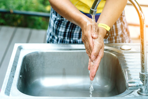 Женщина, мывшая руки с крана с розовым мылом в алюминиевой ванне. Вирус гриппа, Ковид-19 (коронавирусная болезнь). Селективный фокус
. - Фото, изображение