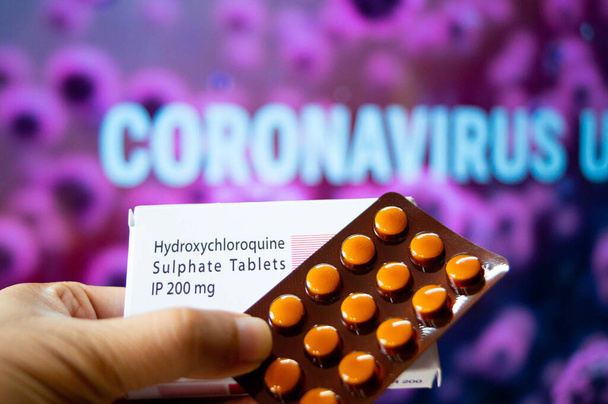 コロナウイルスの流行が記載された赤い色の板の前の白い色の箱の中のヒドロキシクロロキン硫酸表の写真 - 写真・画像