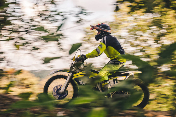 Egy motoros versenyez a motorjával az erdőben. - Fotó, kép