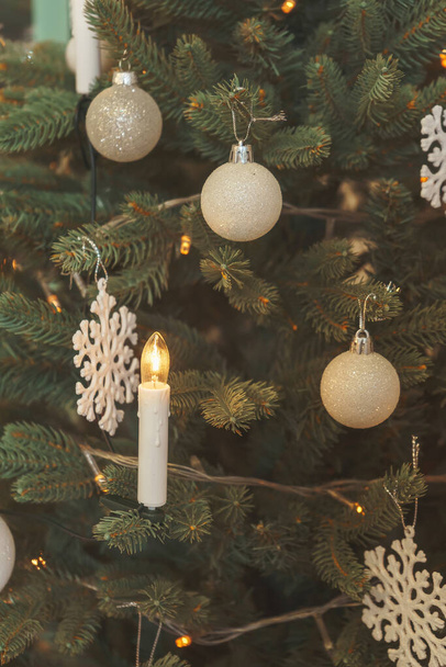 クリスマスツリー上のキャンドルの形でガーランド。クリスマスツリーの近くに白い装飾ボール雪の結晶。偽の人工クリスマスツリー - 写真・画像