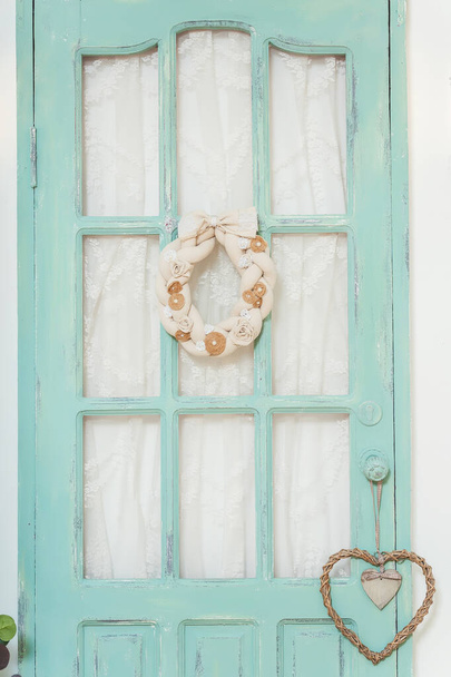 Uma coroa de tecido de tecido de linho de serapilheira na porta. Grinalda de primavera para a casa na porta verde. Grinalda feita à mão de perto
 - Foto, Imagem