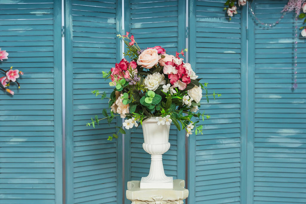 青い屏風の背景に白い花瓶に花を咲かせます。ガラスビーズの花の配置装飾と青の木製の折りたたみ画面。木製のルーブル。花と室内ルーバー折りたたみ画面 - 写真・画像