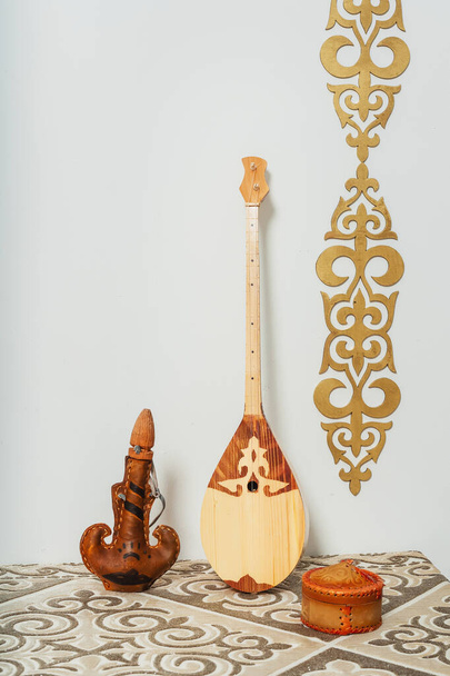 Kazah nemzeti hangszer dombra fehér háttérrel. Nemzeti Kazah díszíteni arany dísztárgyak és háztartási cikkek. Kazah kirgiz etnikai háttér - Fotó, kép