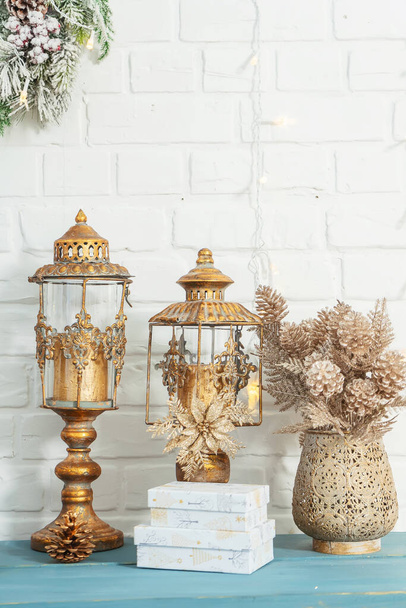 Golden cones on branches in a golden carved oriental vase. Christmas decoration of home interior decor in gold style with cute cozy little things. Gold metal vintage candlesticks lanterns with glass - Photo, Image