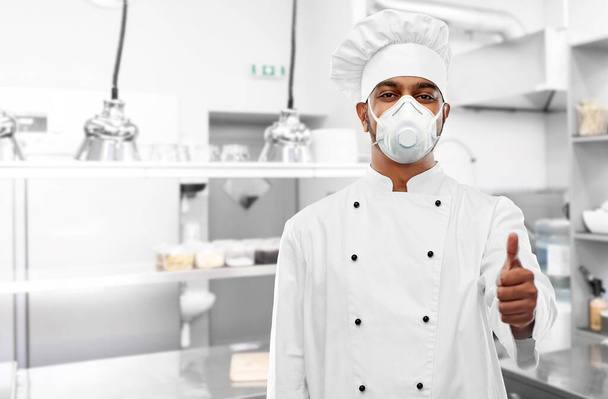 chef in respirator showing thumbs up at kitchen - Foto, Imagem