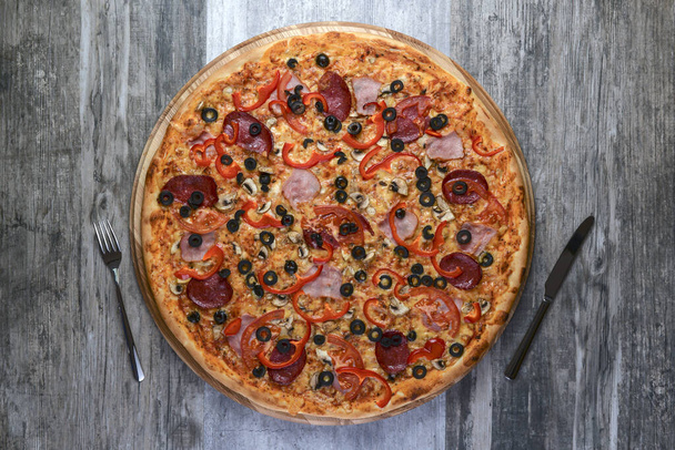 Flat lay photograph of tasty italian pizza on rustic wood. Pepperoni, cheese and peppers. Delicious food. - Foto, afbeelding