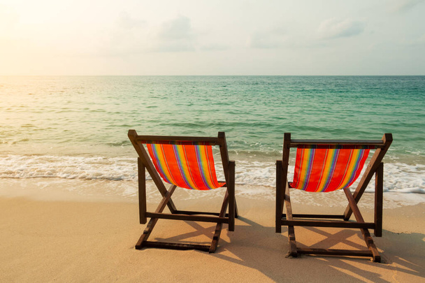 Duas cadeiras de praia na praia de areia com a luz do sol
 - Foto, Imagem