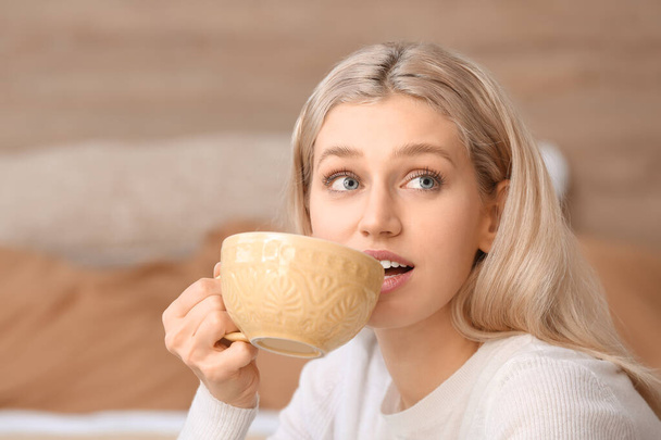 Beautiful young woman drinking tea at home - Fotografie, Obrázek
