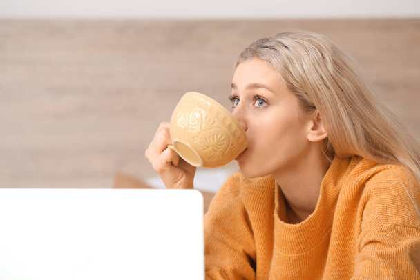 Mooie jonge vrouw die thuis thee drinkt - Foto, afbeelding