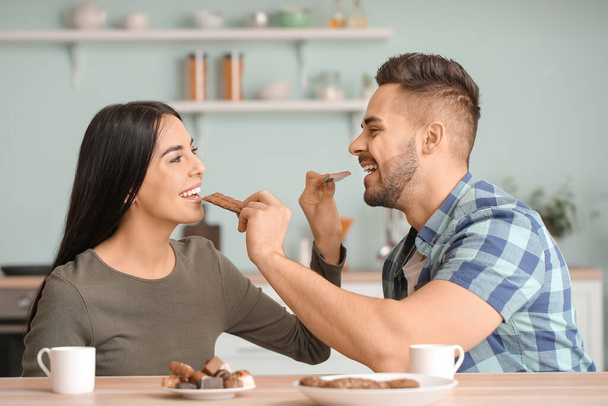 Hermosa pareja joven comiendo chocolate en la cocina
 - Foto, Imagen