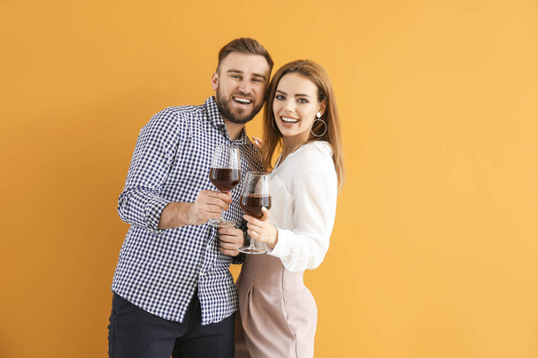 Ευτυχισμένο ζευγάρι με ποτήρια κρασί στο φόντο του χρώματος - Φωτογραφία, εικόνα