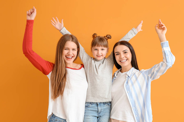 Happy lesbian couple with little adopted girl on color background - Photo, Image