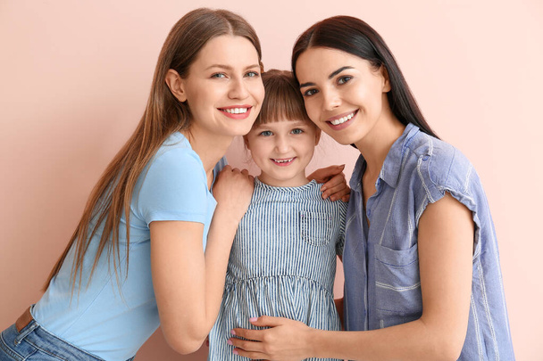 Glückliches lesbisches Paar mit wenig Adoptivmädchen auf farbigem Hintergrund - Foto, Bild