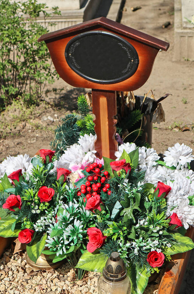 Flores en la tumba en el cementerio público
 - Foto, Imagen