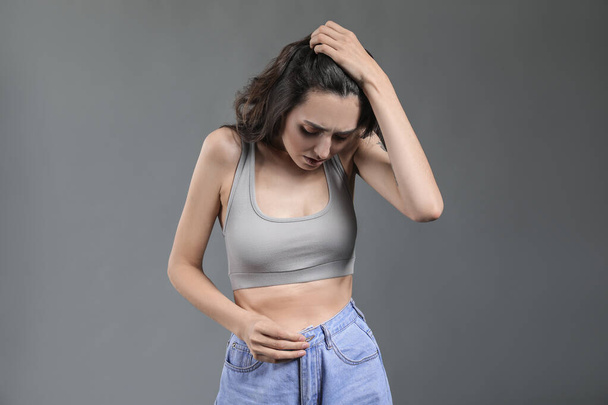 Mujer joven con anorexia sobre fondo gris
 - Foto, Imagen