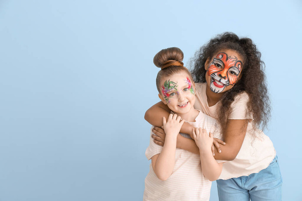 Zabawne małe dzieci z malowaniem twarzy na tle koloru - Zdjęcie, obraz