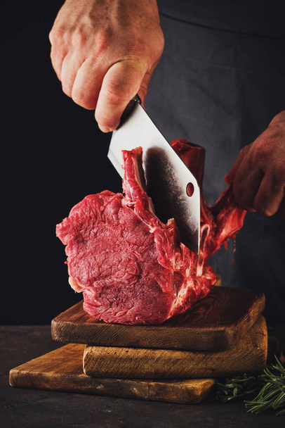 Carnicero macho corta carne cruda de res
 - Foto, Imagen