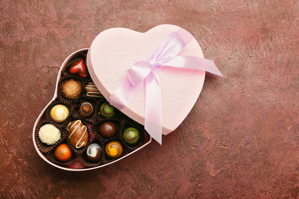 Heart-shaped box with delicious candies on color background - Photo, Image