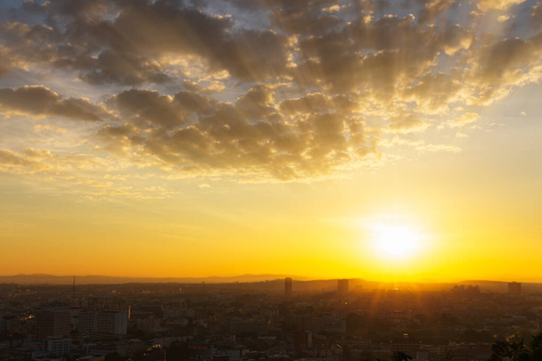 日の出のパタヤ市。パタヤの南、プラトゥムナックヒルの視点から撮影された、街の上に輝く太陽の黄金の光. - 写真・画像