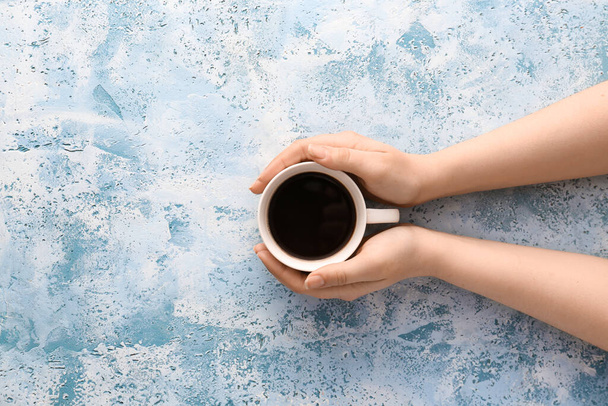 Γυναικεία χέρια με φλιτζάνι ζεστό καφέ στο φόντο χρώμα, top view - Φωτογραφία, εικόνα