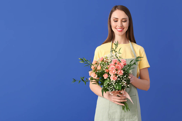 Portrait of female florist with bouquet on color background - Foto, Imagen