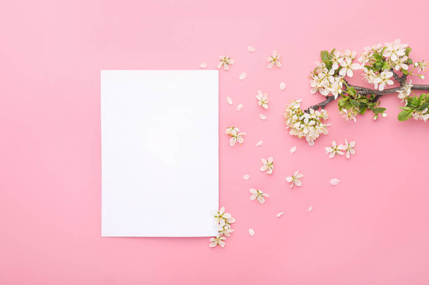 Beautiful blossoming branch and blank paper on color background - Foto, imagen