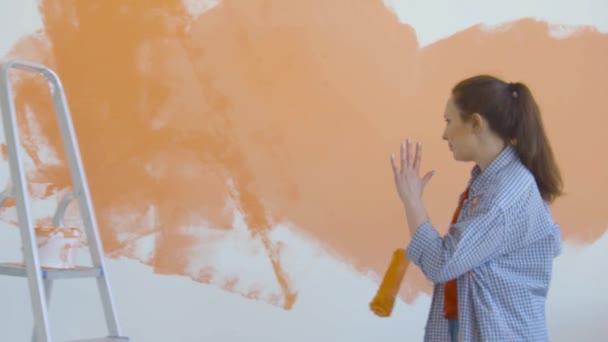 Estilo de vida único e conceito de renovação. Jovem mulher sorridente com pintura rolo pinta a parede no apartamento e dança
 - Filmagem, Vídeo