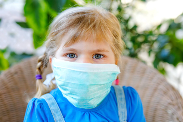 little toddler girl in medical mask as protection against pandemic coronavirus quarantine disease. Cute child using protective equipment as fight against covid 19. - Photo, Image