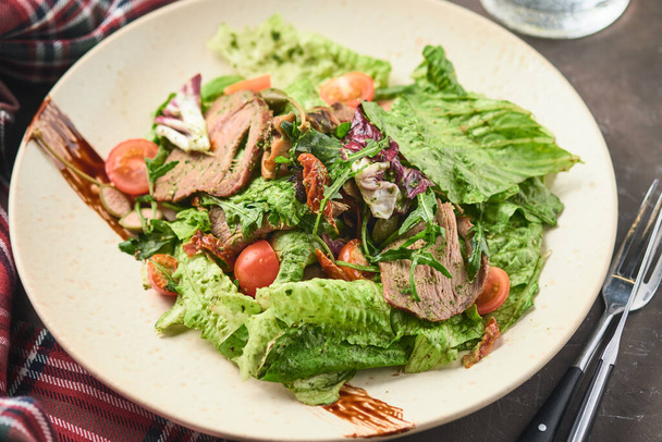 Warmer Salat mit Rindfleisch, Kirschtomaten und sonnengetrockneten Tomaten. Gesunde Ernährung. - Foto, Bild