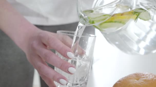 Slow motion of unrecognizable woman pouring infused water into glass and drinking detox cocktail. Young Caucasian lady dieting and taking care of health with organic drink. Lifestyle. Slowmo. - Filmagem, Vídeo