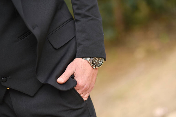 Armbanduhren in Nahaufnahme, Anzug, Männerstil, stilvoller Mann. Eleganter junger gutaussehender Mann. Männerjacke, Hand bedeckt den Knopf. Geschäftsstile. - Foto, Bild