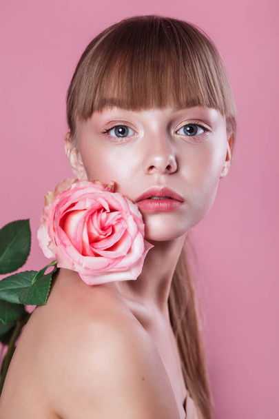 Beauty portrait of beautiful woman model with fresh daily makeup and rose on pink studio background - Fotó, kép