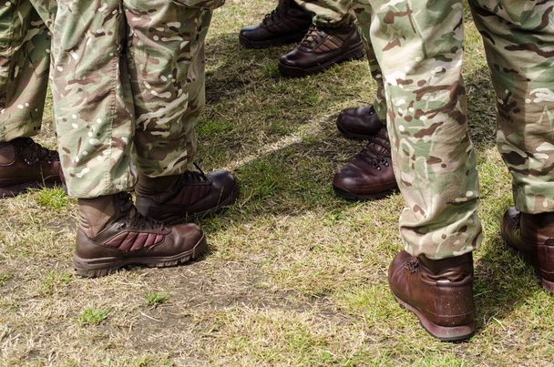 Καφέ μπότες που φοριούνται από Βρετανούς στρατιώτες με τη στολή καμουφλάζ. - Φωτογραφία, εικόνα