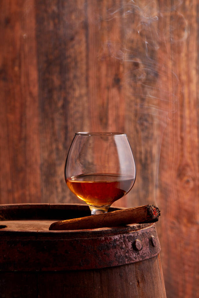 Bicchiere di cognac su fusto di legno e sigaro
 - Foto, immagini