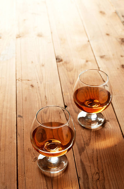 Glasses of cognac on old wooden table - Fotoğraf, Görsel