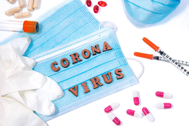 Medical equiment, mask and pills around letters of words corona virus on white background. Virus pandemic protection alert concept - Foto, Imagem