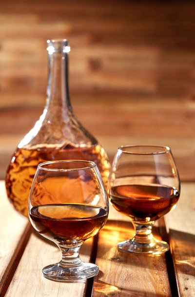 Glasses and bottle of cognac on old wooden table - Fotografie, Obrázek