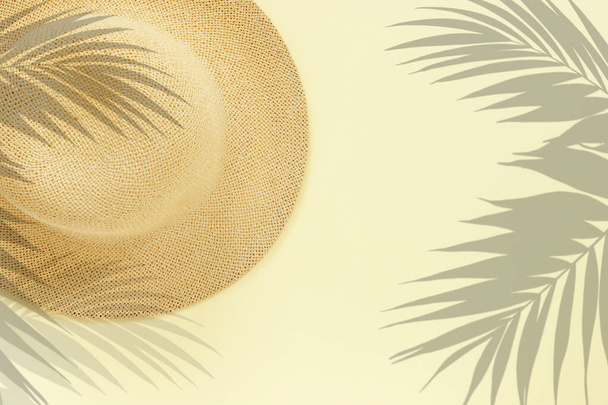 Fashionable straw hat with palm leaves on yellow paper backgroun - 写真・画像