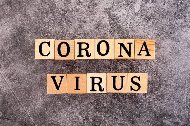 Τα γράμματα στο ξύλο που έγραψε τη λέξη Coronavirus στο μαύρο τσιμεντένιο φόντο. - Φωτογραφία, εικόνα