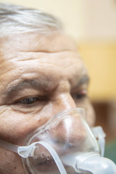 Starszy mężczyzna używający sprzętu medycznego do inhalacji z maską oddechową, nebulizator w pokoju - Zdjęcie, obraz
